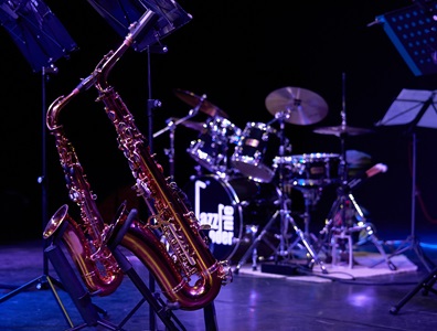 Zwei Saxophone vor Schlagzeug auf dunkler Bühne