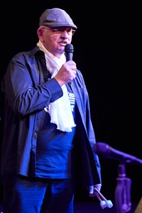Axel Großmann mit Mikrofon in der Hand vor schwarzem Bühnenhintergrund