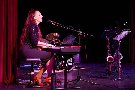 Linda Jesse performt ihren Song "too loud" am Piano auf der Bühne
