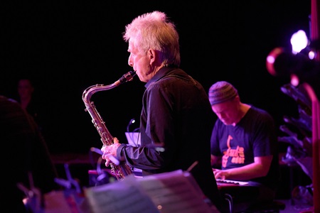 Harry Wesolowski am Saxophon im Scheinwerferlicht vor Dieter Gutfried